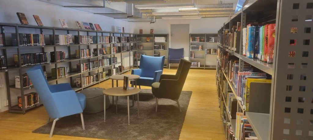 Bilde fra Hol folkebibliotek som viser sittegruppe og hyller med bøker.