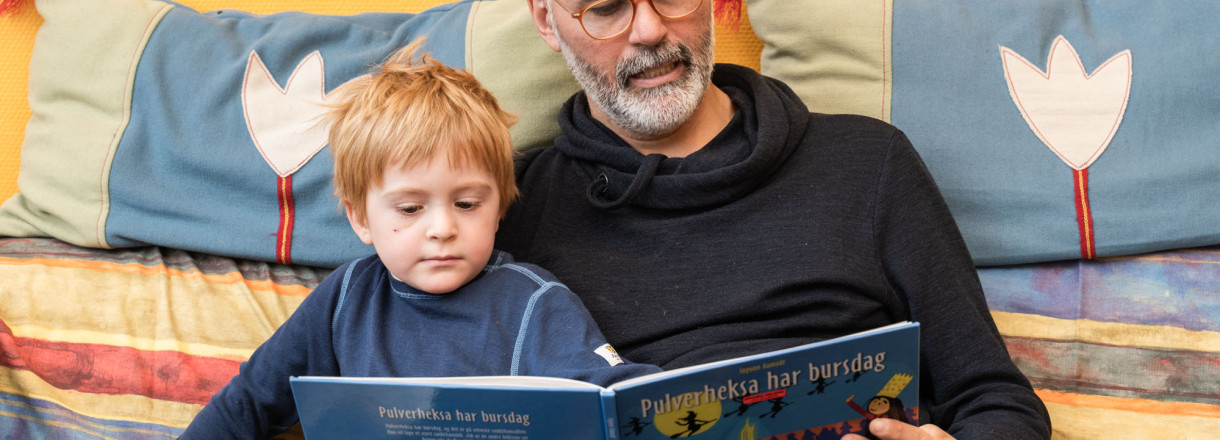 Bilde av en mann og en gutt som leser sammen.