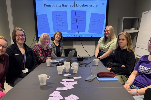 Bilde av personer som sitter rundt et bord og snakker om digital kildebevissthet.